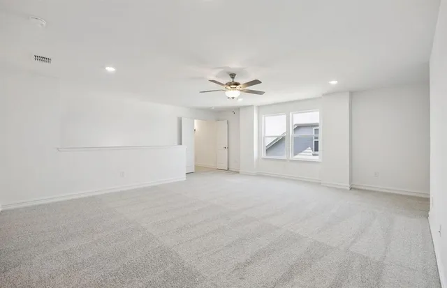 an empty room with chandelier fan and windows
