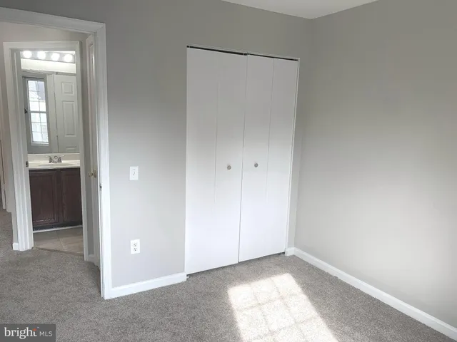 a view of an empty room with closet and a bathroom