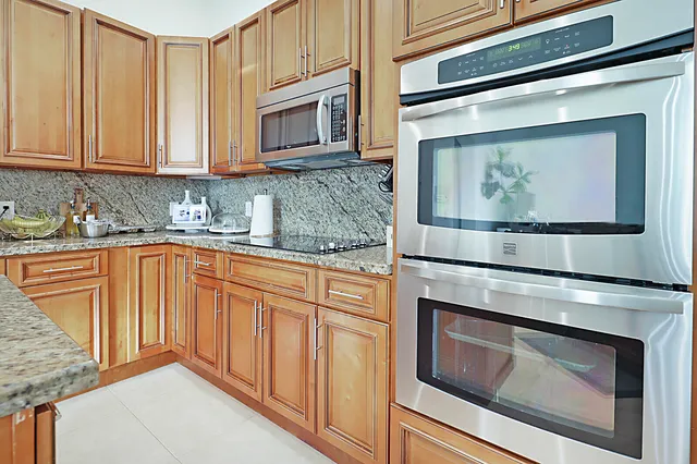 a kitchen with stainless steel appliances granite countertop white cabinets and a stove top oven