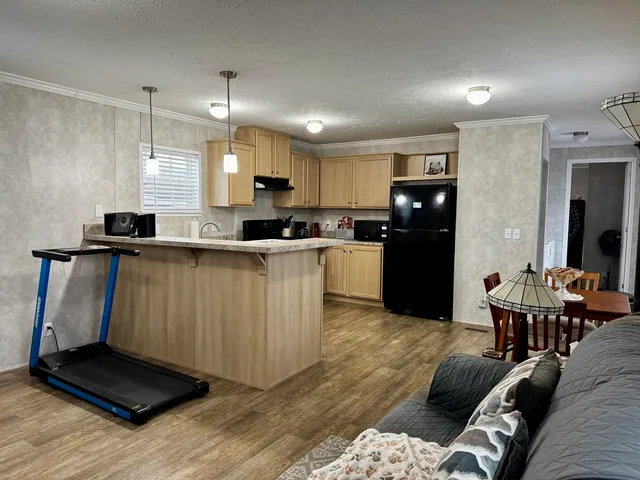 a kitchen with stainless steel appliances kitchen island granite countertop a refrigerator a stove a sink a dining table and chairs with wooden floor