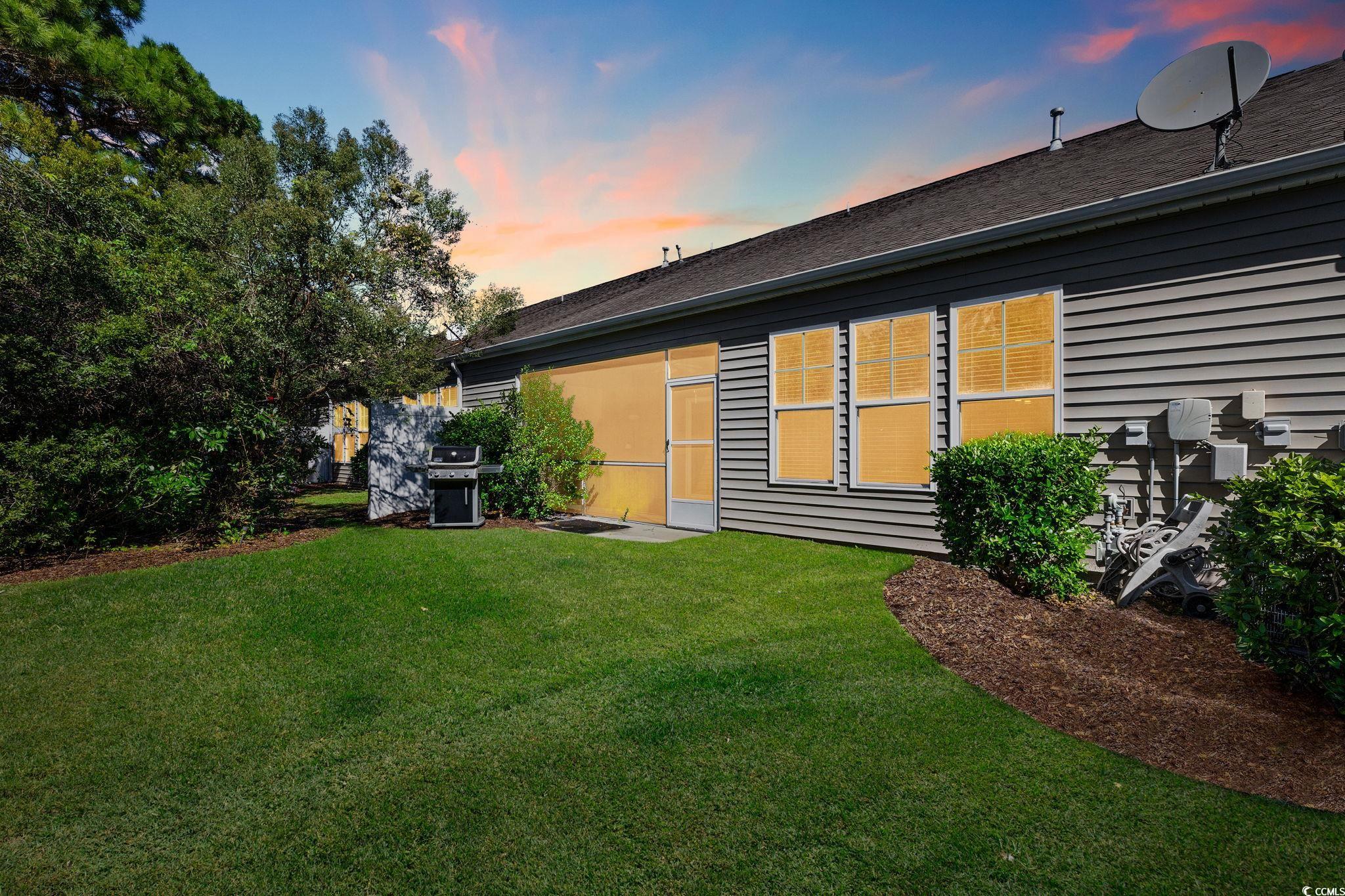 817 Arezzo Way, Unit 1001 Myrtle Beach, SC 29579 - Photo 35 of 40 Back of property at dusk featuring a yard and a shingled roof