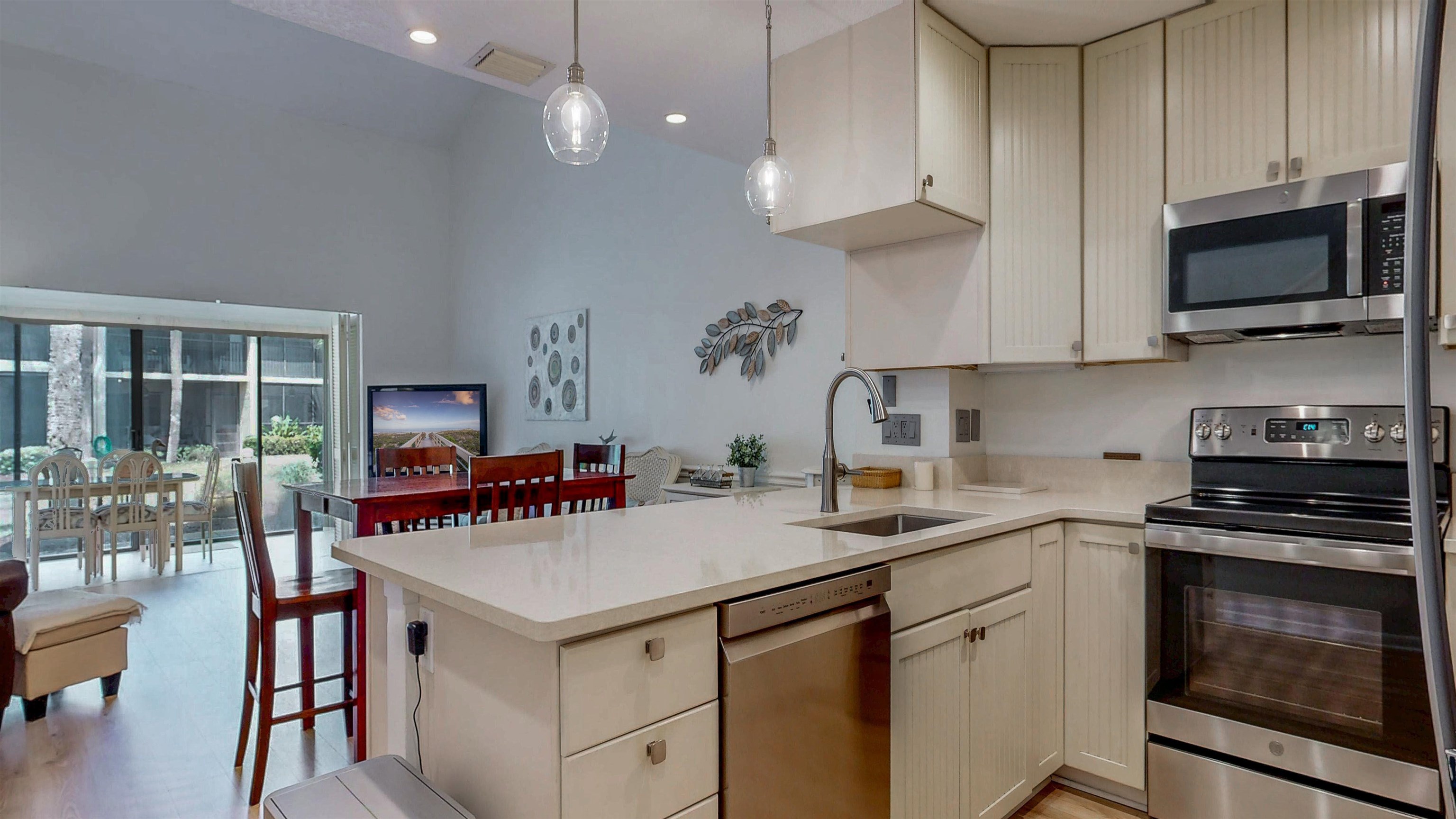 82 Village Las Palmas Circle St. Augustine, FL 32080 - Photo 13 of 58 Kitchen featuring stainless steel appliances, a peninsula, light stone counters, a high ceiling, and hanging light fixtures