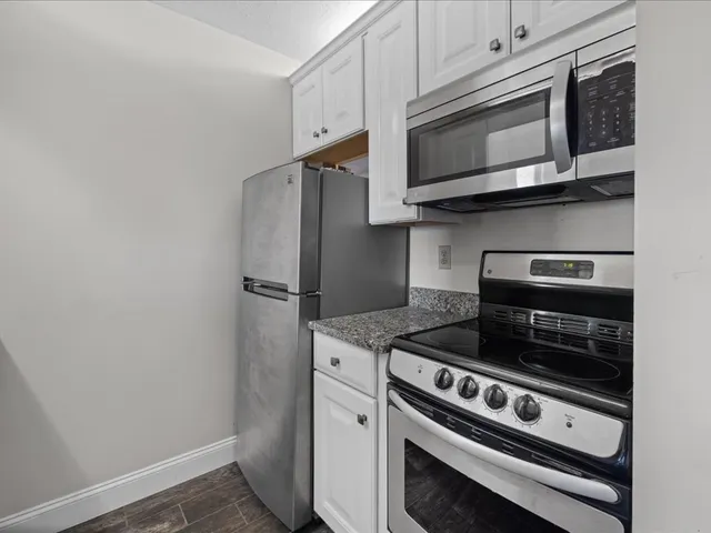 a kitchen with granite countertop white cabinets and a sink