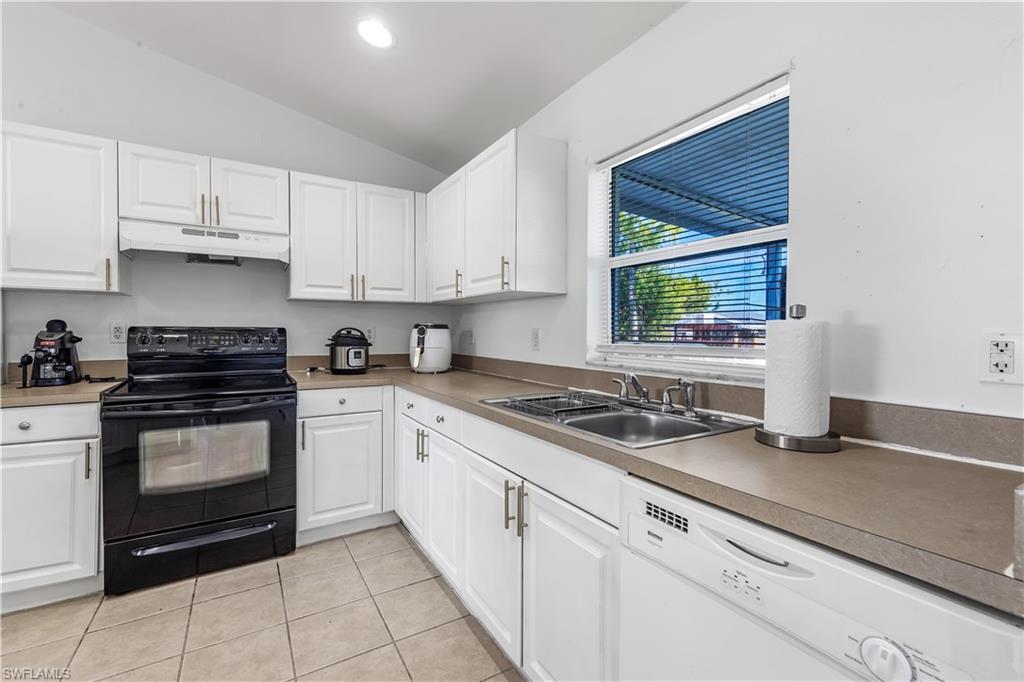 681-683 Alabama Road South, Unit 683 Lehigh Acres, FL 33974 - Photo 24 of 35 a kitchen with granite countertop white cabinets stainless steel appliances a sink and a window