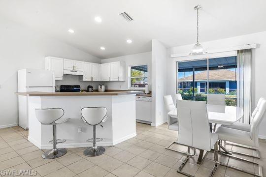 681-683 Alabama Road South, Unit 683 Lehigh Acres, FL 33974 - Photo 28 of 35 a kitchen with kitchen island granite countertop a dining table chairs and white cabinets