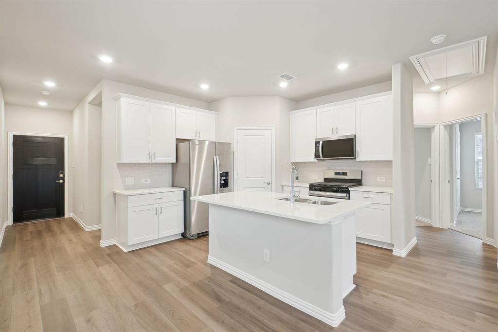 a kitchen with a refrigerator a stove top oven and white cabinets