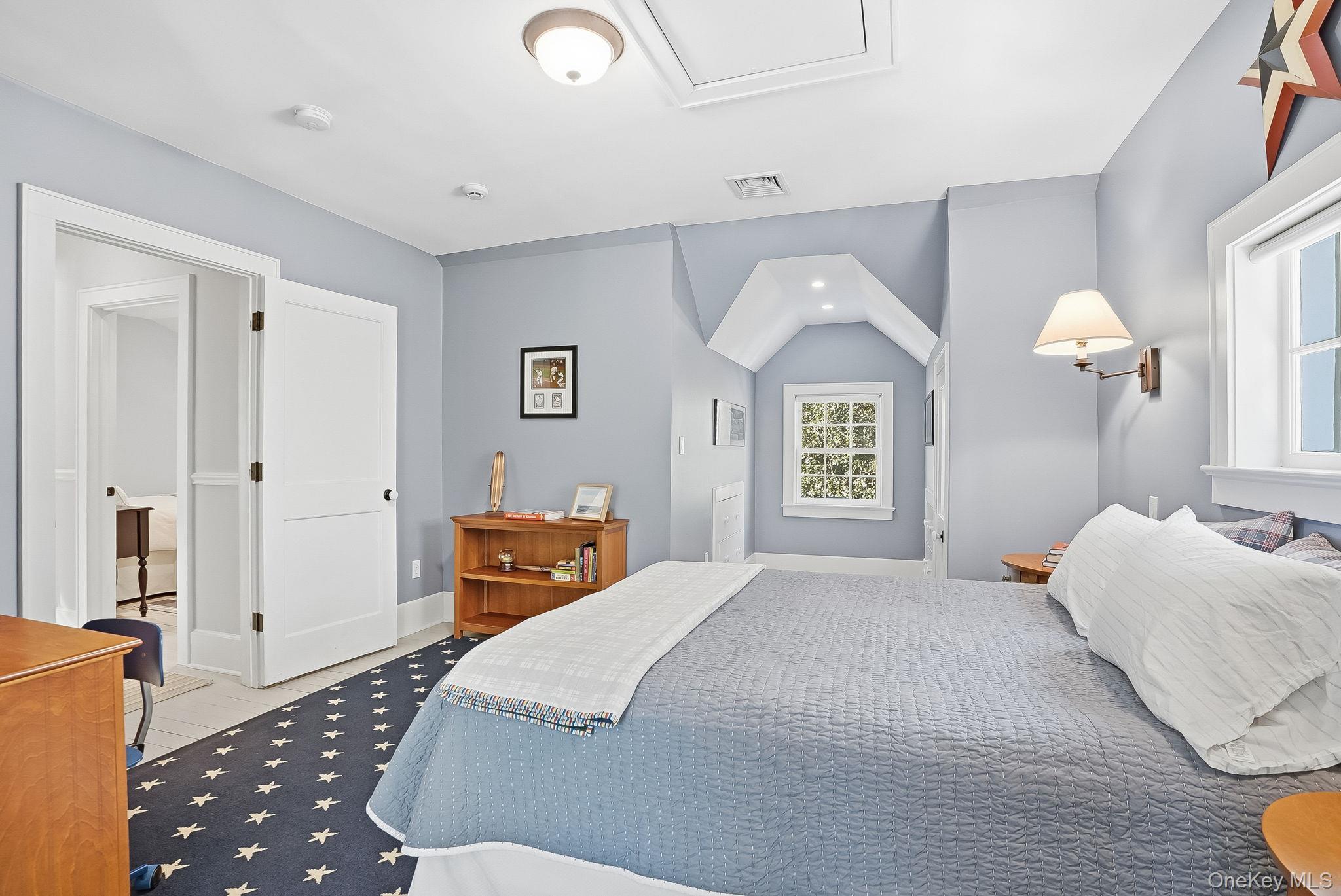 880 Forest Avenue Rye, NY 10580 - Photo 35 of 48 a bedroom with a bed and a lamp on dresser with wooden floor