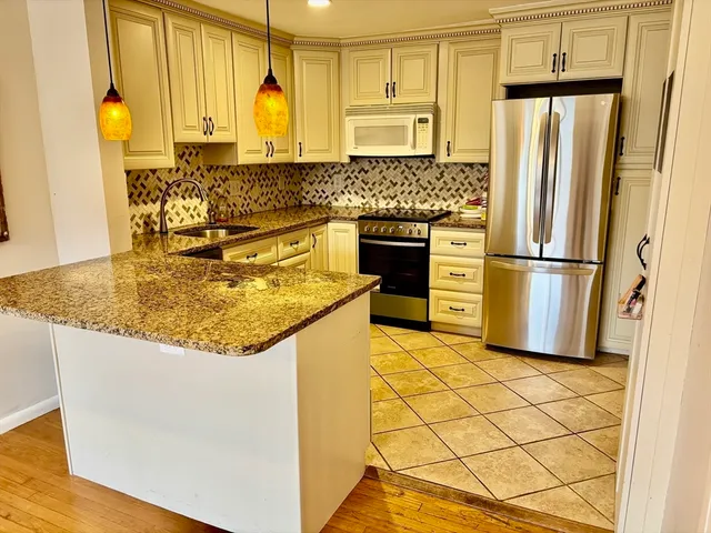 a kitchen with stainless steel appliances granite countertop a refrigerator a stove and a sink