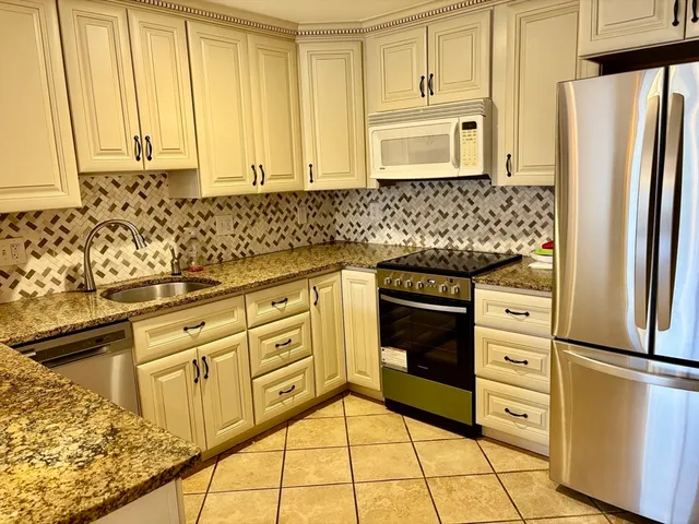 a kitchen with granite countertop white cabinets and stainless steel appliances