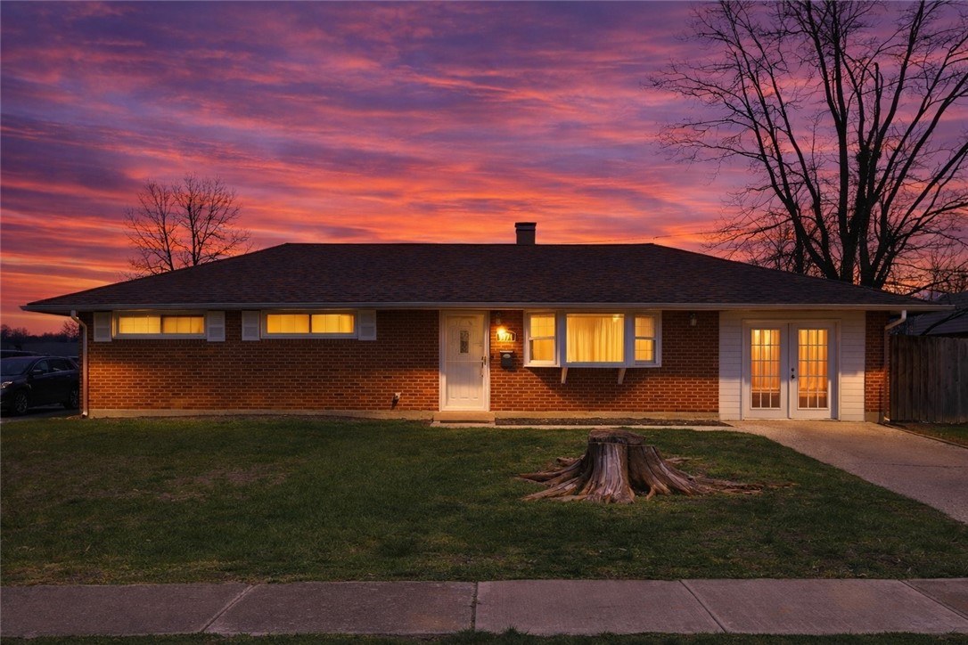 5171 Fishburg Road Dayton, OH 45424 - Photo 2 of 35 This classic brick residence, illuminated by a vibrant sunset, offers a welcoming facade and mature landscaping.