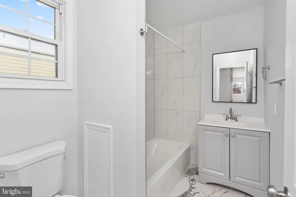 a bathroom with a tub sink toilet and mirror