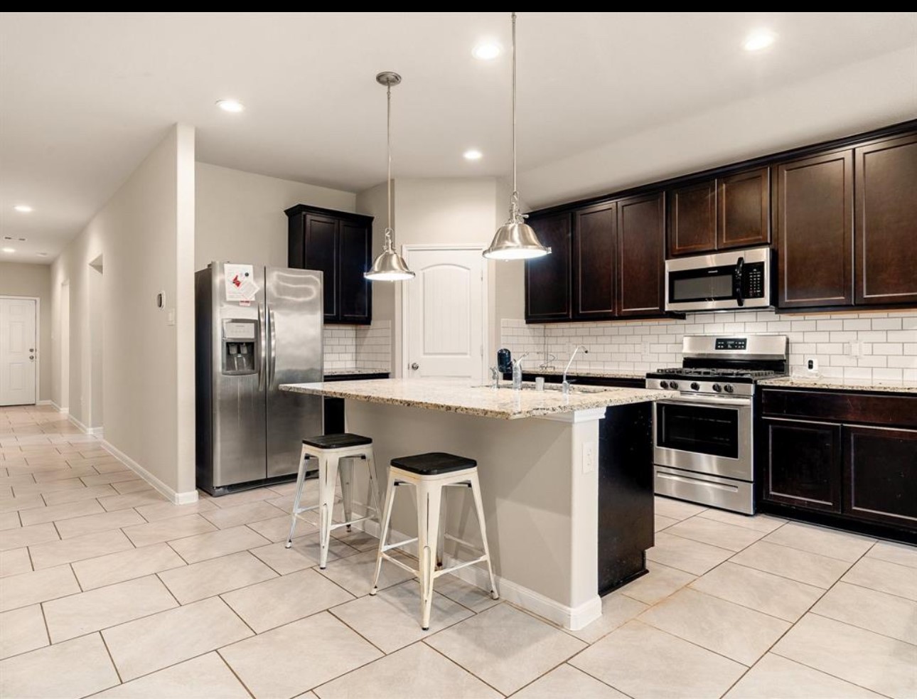 8307 Oakleaf Meadow Court Rosharon, TX 77583 - Photo 2 of 11 a large kitchen with stainless steel appliances kitchen island granite countertop a stove a sink and a microwave
