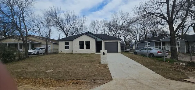 a front view of a house with a garden and trees