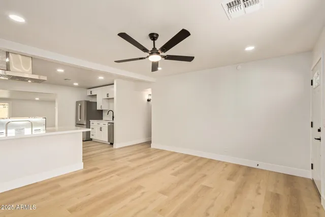 a view of a livingroom with a kitchen island stainless steel appliances wooden floor and a refrigerator