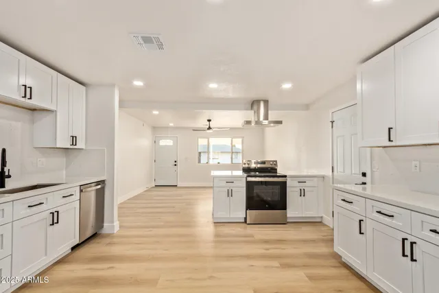 a large kitchen with stainless steel appliances kitchen island granite countertop a stove and a sink