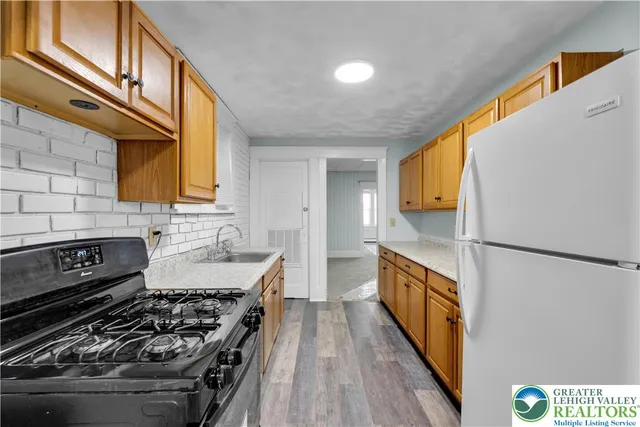 a kitchen with stainless steel appliances granite countertop a refrigerator a stove and a sink