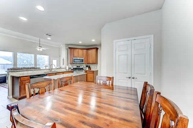 a large open kitchen with stainless steel appliances granite countertop a stove a sink a refrigerator and white cabinets with wooden floor