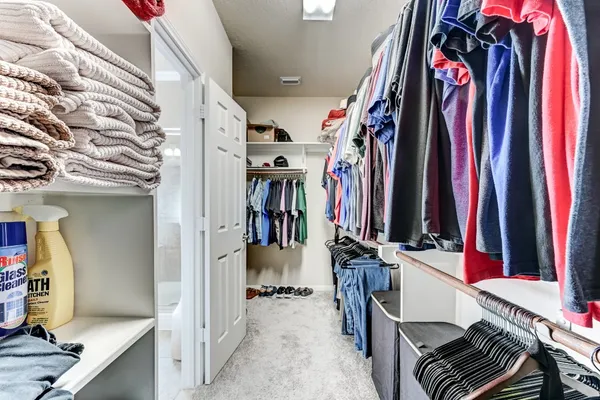 a view of walk in closet with clothes and shoes