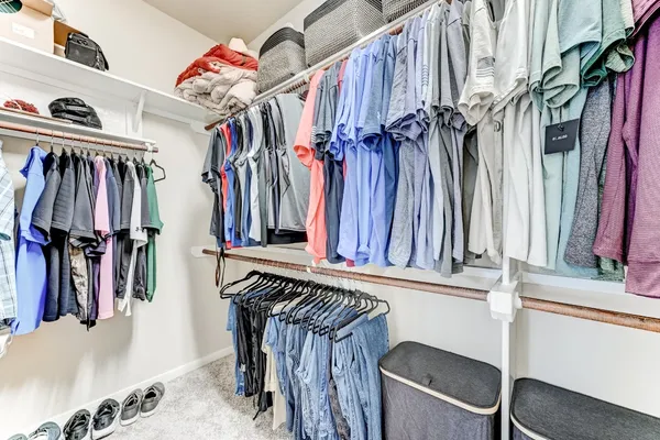 a view of walk in closet with clothes and shoes