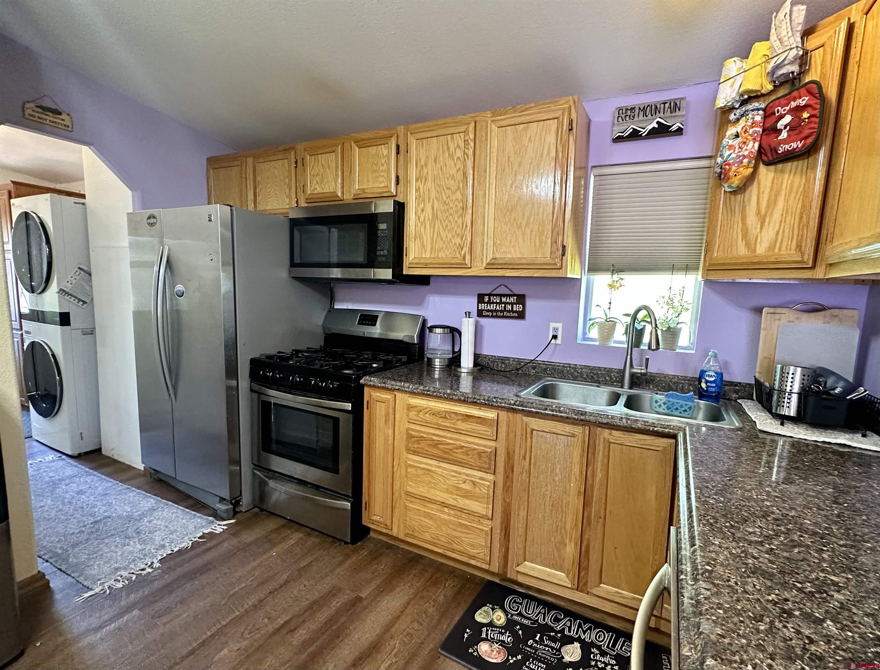 6000 County Road 203, Unit 55 Durango, CO 81301 - Photo 8 of 33 a kitchen with stainless steel appliances granite countertop a refrigerator a sink dishwasher a stove a dining table and chairs with wooden floor