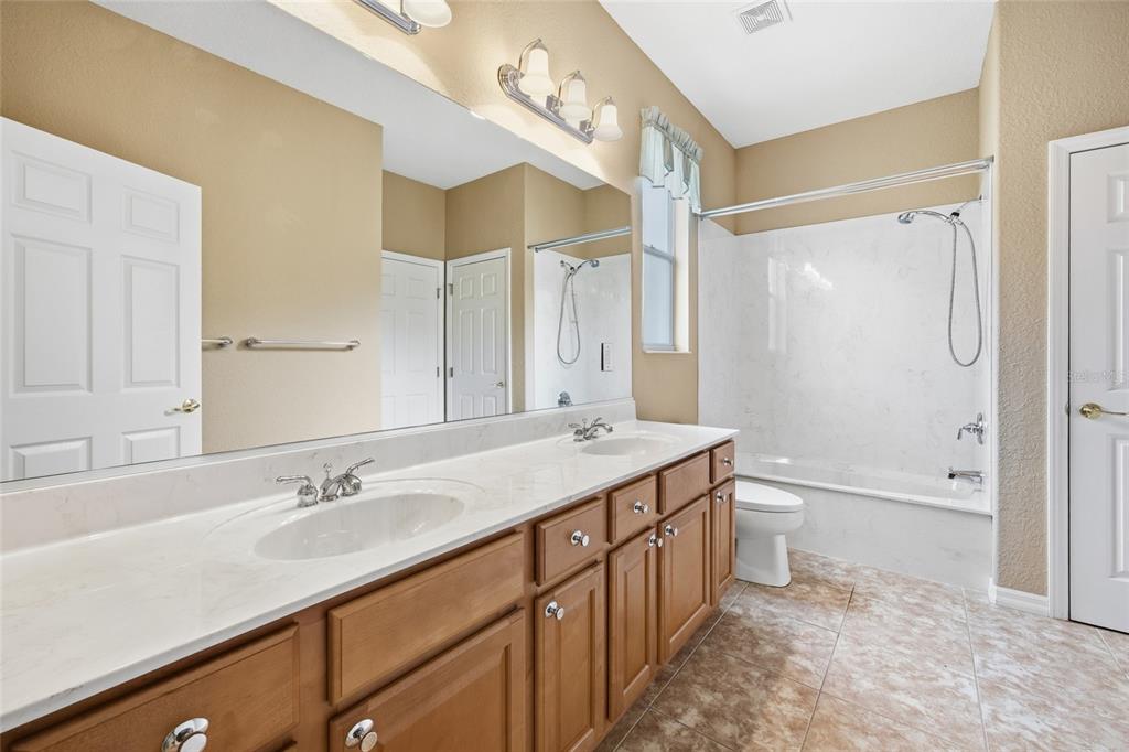 9029 Southeast 130th Loop Summerfield, FL 34491 - Photo 31 of 55 a bathroom with a double vanity sink toilet mirror and bathtub