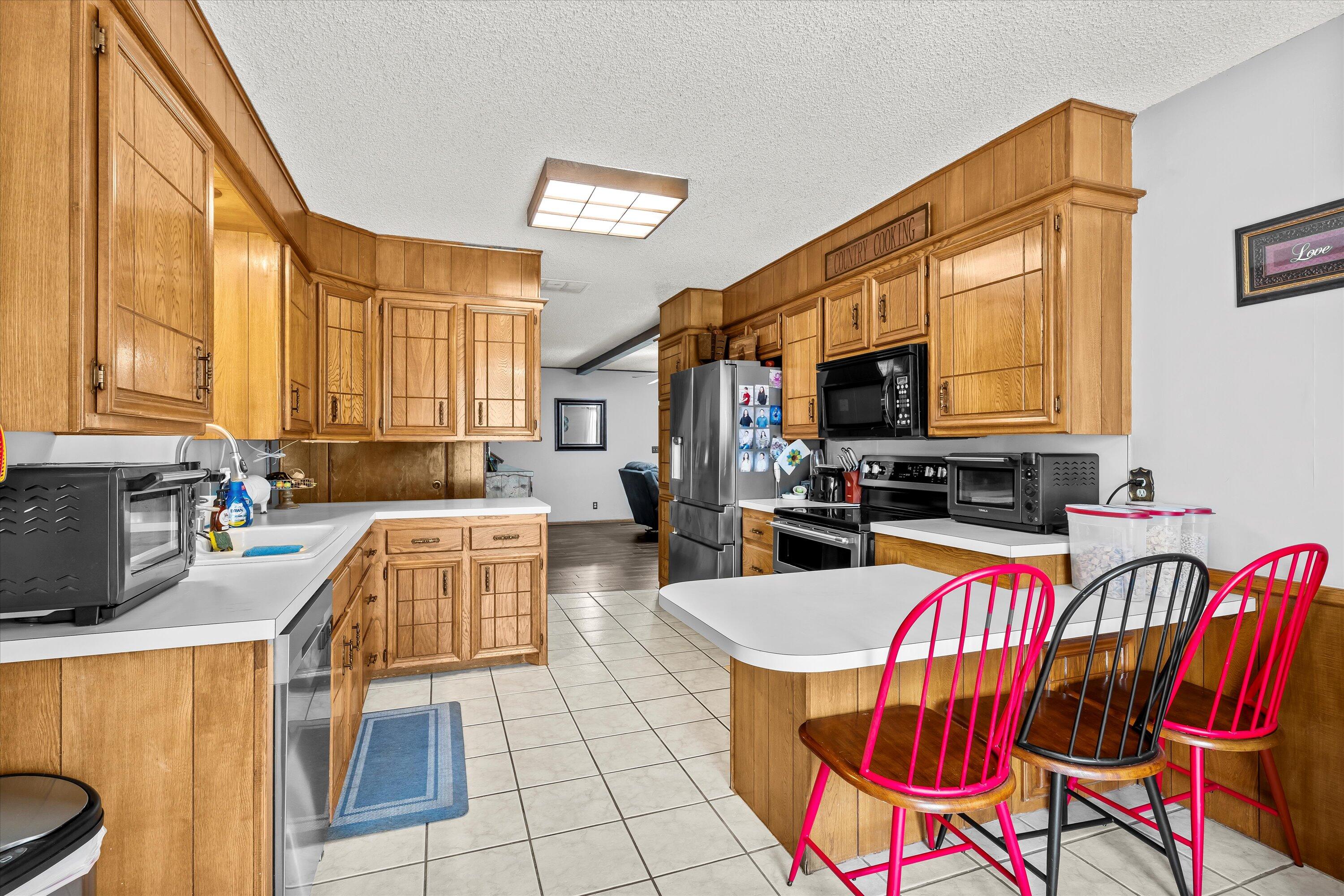 116 East 26th Street Littlefield, TX 79339 - Photo 14 of 40 a kitchen with stainless steel appliances granite countertop a stove a sink dishwasher a dining table and chairs with wooden floor