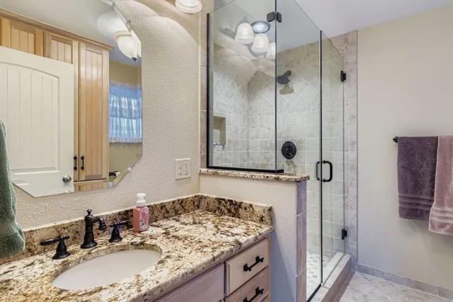 a bathroom with a granite countertop sink a mirror and shower