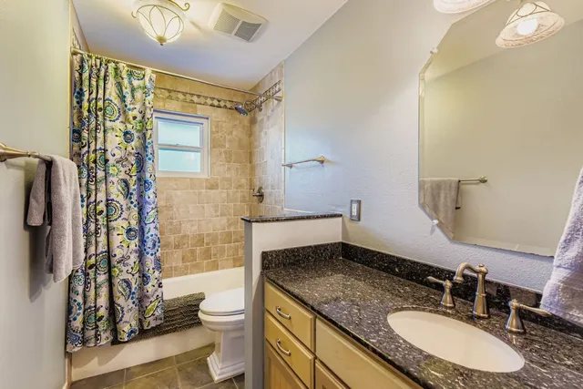 a bathroom with a granite countertop sink toilet and shower