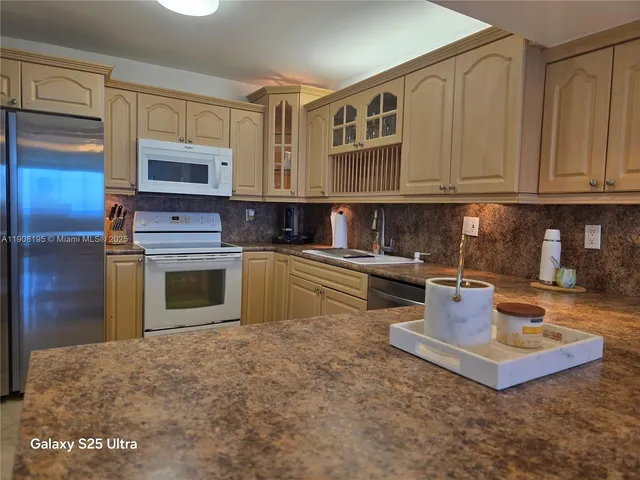 a kitchen with stainless steel appliances granite countertop a stove a sink dishwasher and a microwave oven with white cabinets