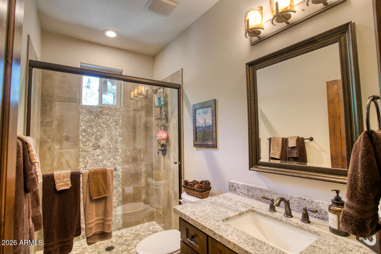4880 West Hawthorn Road Show Low, AZ 85901 - Photo 14 of 42 a bathroom with a granite countertop sink a mirror and a shower