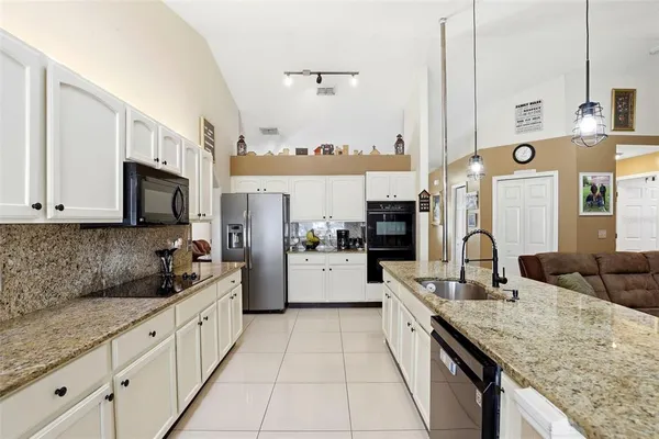 a large kitchen with granite countertop a sink and cabinets