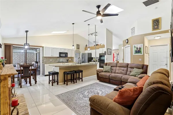 a living room with furniture kitchen view and a chandelier