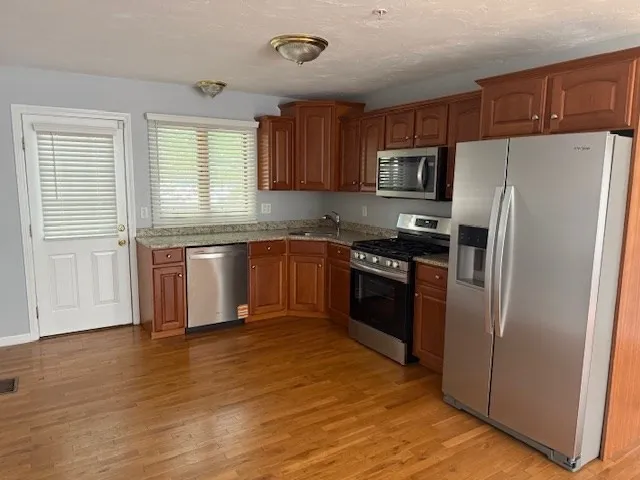 a kitchen with stainless steel appliances granite countertop a refrigerator stove a sink and dishwasher with wooden floor