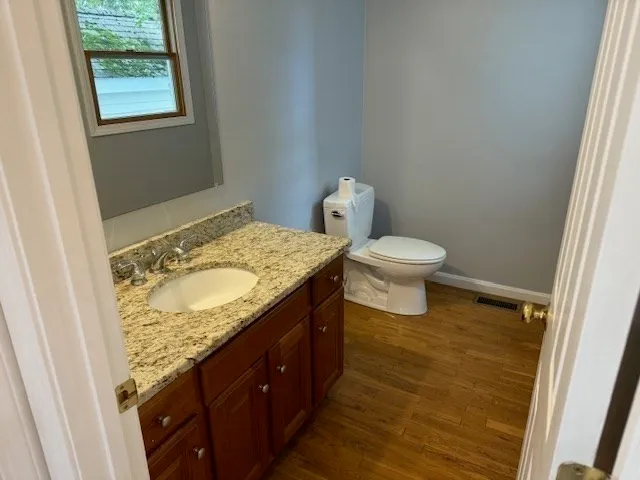 a bathroom with a granite countertop sink and a toilet
