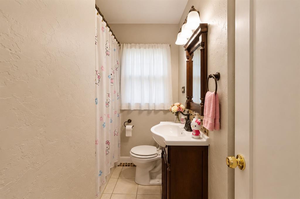 10505 Ferguson Road Dallas, TX 75228 - Photo 12 of 14 Bathroom featuring a dark wood vanity with an integrated sink, a matching framed mirror, and a three-light fixture