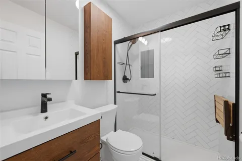 a bathroom with a sink a toilet a mirror and shower