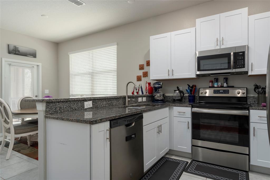 11704 Castine Street New Port Richey, FL 34654 - Photo 18 of 31 a kitchen with stainless steel appliances granite countertop white cabinets granite counter tops and a window