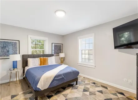 a bed room with a bed television and a window