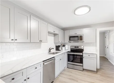 a kitchen with stainless steel appliances a sink a stove a microwave and cabinets