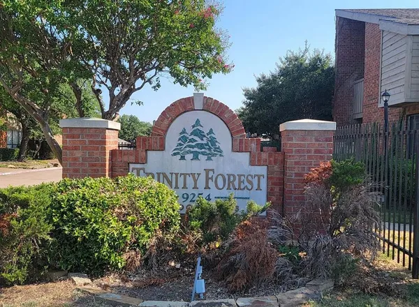 a view of a sign board with a house in the background
