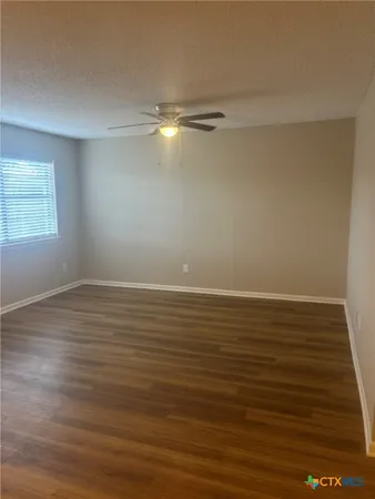 a view of an empty room with wooden floor and windows
