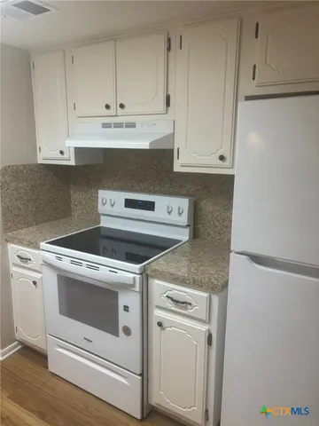 a kitchen with granite countertop white cabinets and white appliances