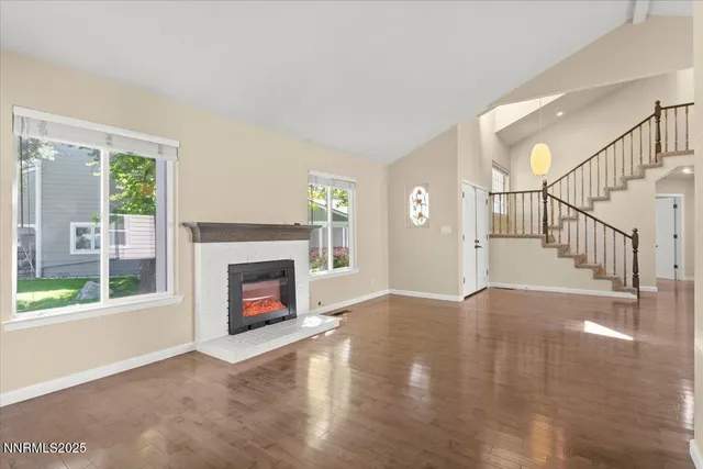 a view of an empty room with wooden floor fireplace and a window