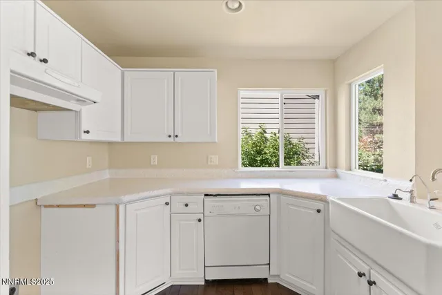 a kitchen with white cabinets and a window
