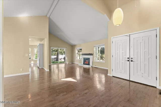 a view of an empty room with window and wooden floor