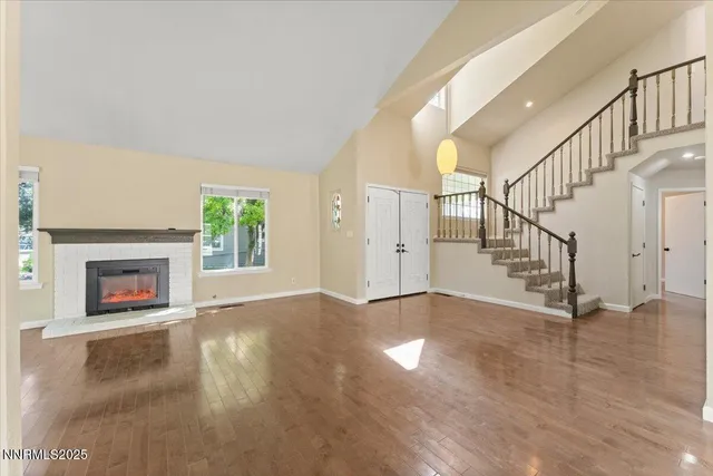a view of an empty room with wooden floor fireplace and a window