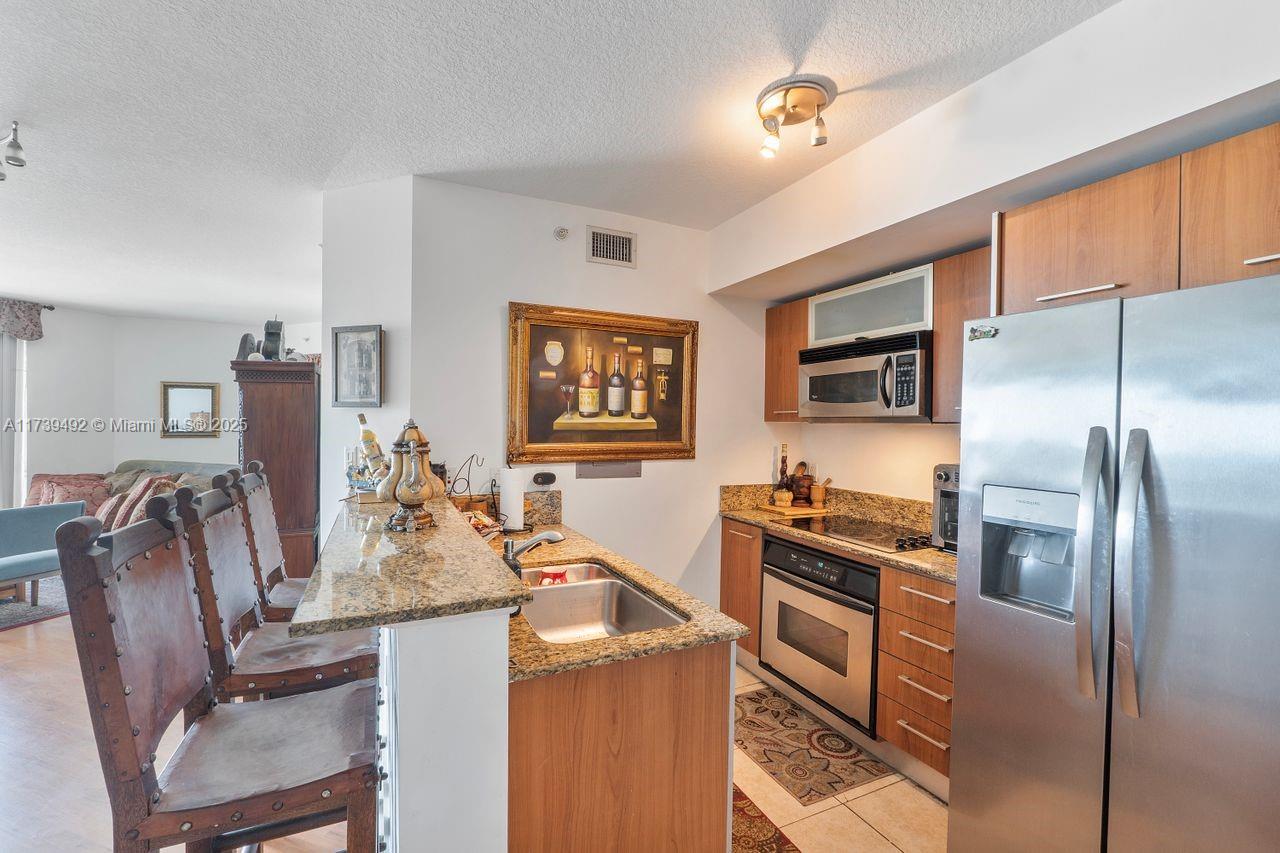 9055 Southwest 73rd Court, Unit 903 Miami, FL 33156 - Photo 21 of 24 a kitchen with stainless steel appliances granite countertop a stove refrigerator and a dining table