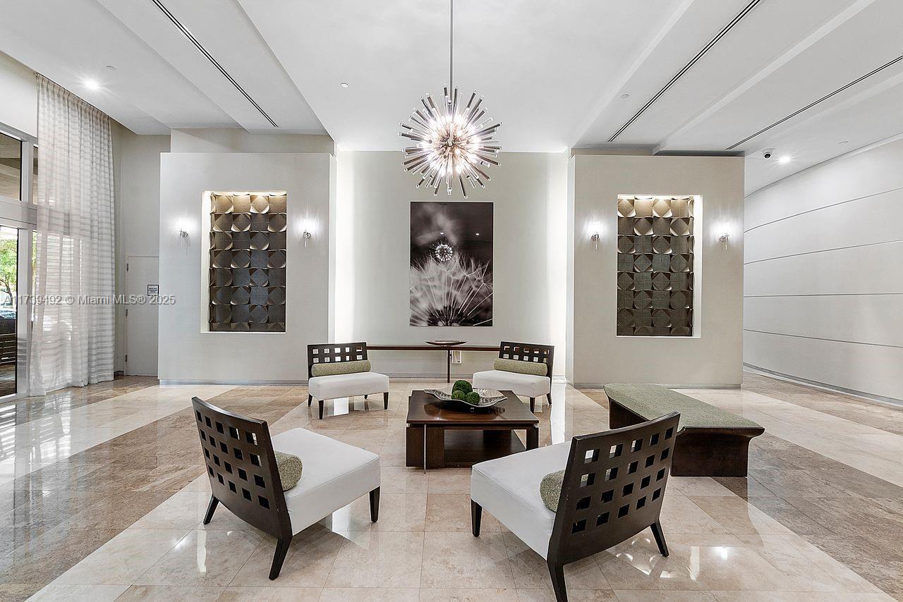 9055 Southwest 73rd Court, Unit 903 Miami, FL 33156 - Photo 8 of 24 a living room with furniture and a chandelier