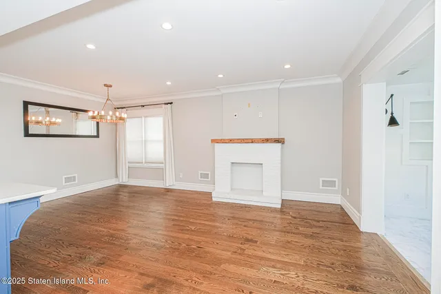 a view of empty room with wooden floor and window