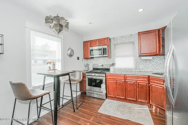 a kitchen with stainless steel appliances granite countertop a stove top oven a sink dishwasher and chairs with wooden floor